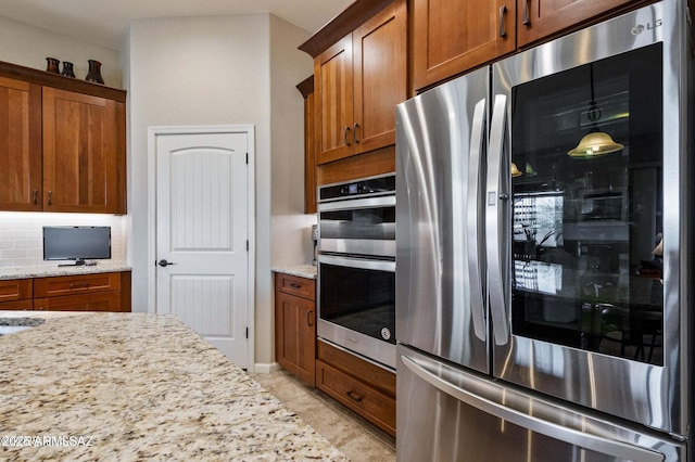 kitchen featuring decorative backsplash, appliances with stainless steel finishes, and brown cabinetry