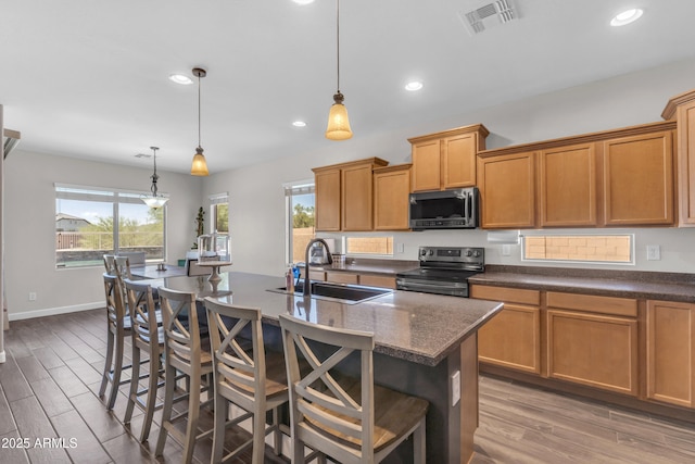 23886 W Harrison Dr, Buckeye, AZ 85326 - kitchen featuring stainless steel appliances, light wood-style floors, a breakfast bar, a kitchen island with sink, and recessed lighting