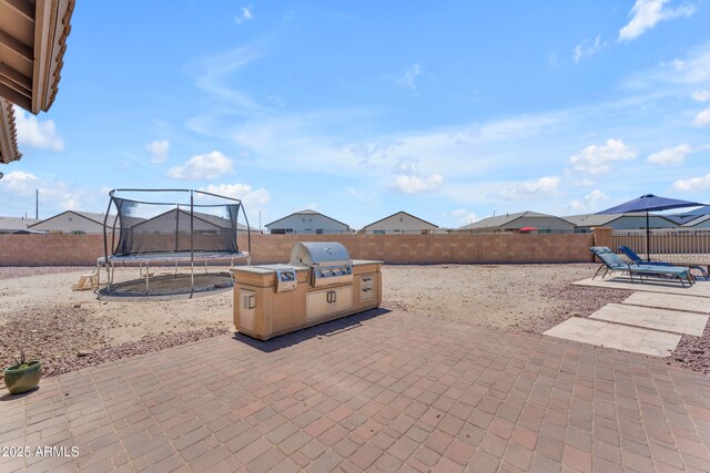 23886 W Harrison Dr, Buckeye, AZ 85326 - fenced backyard featuring a trampoline, a patio, and an outdoor kitchen
