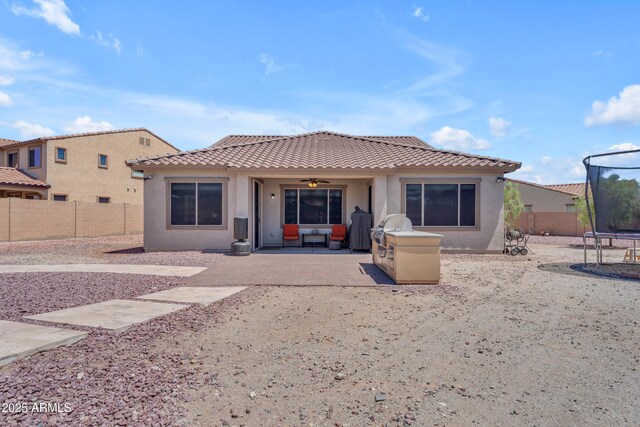 23886 W Harrison Dr, Buckeye, AZ 85326 - back of property featuring a trampoline, a patio, a tiled roof, stucco siding, and a fenced backyard
