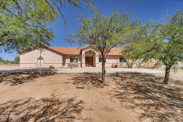 view of front facade with a tiled roof, fence, and stucco siding