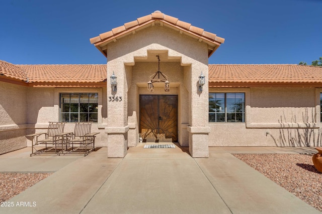 entrance to property with a patio area, a tile roof, and stucco siding