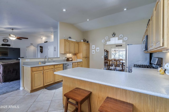 kitchen featuring a breakfast bar area, appliances with stainless steel finishes, a peninsula, light countertops, and a sink