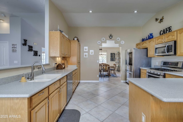 kitchen with light tile patterned floors, a peninsula, a sink, light countertops, and appliances with stainless steel finishes