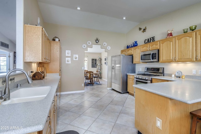 kitchen with stainless steel appliances, light countertops, vaulted ceiling, a sink, and a peninsula