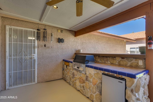 view of patio with ceiling fan, exterior kitchen, and area for grilling