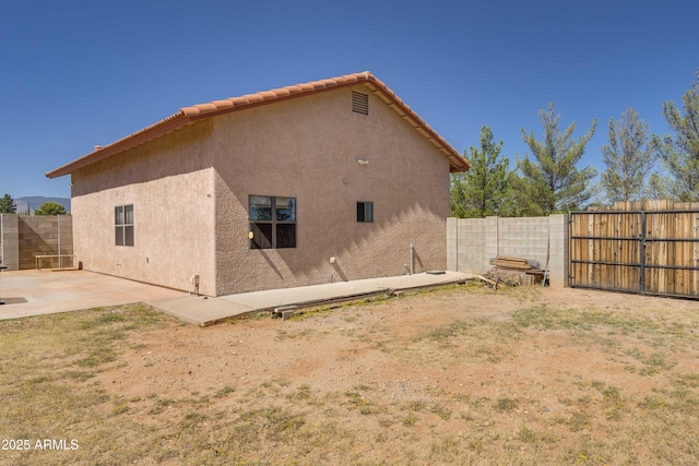 rear view of property featuring a patio, a fenced backyard, and stucco siding