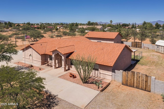 view of front facade featuring a tile roof, stucco siding, a gate, a mountain view, and fence private yard