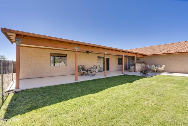 back of house with a patio area, fence, a lawn, and stucco siding