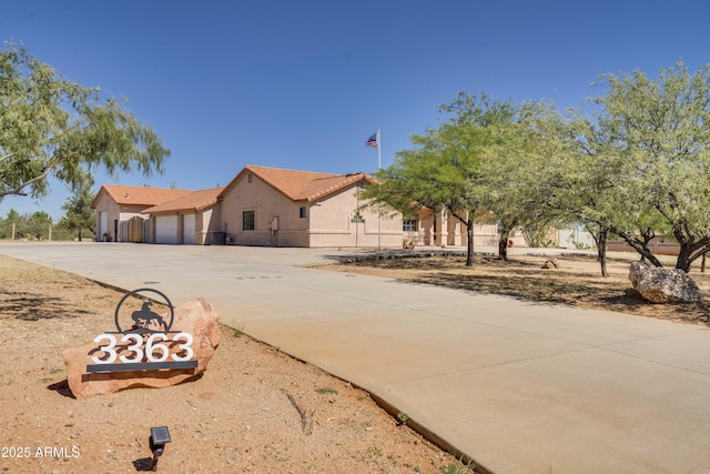 view of front of property featuring an attached garage, a tile roof, concrete driveway, and stucco siding