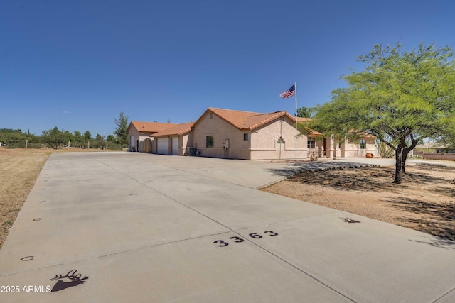 view of front of house featuring a garage, driveway, a tiled roof, and stucco siding