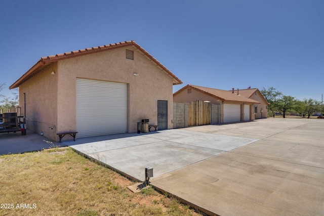 view of side of home with a garage, fence, and stucco siding