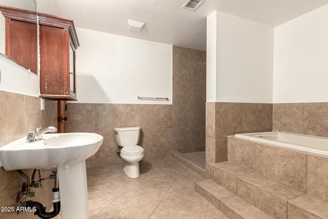 7340 W Meadowbrook Ave, Phoenix, AZ 85033 - bathroom with tile walls, toilet, tile patterned flooring, a bath, and wainscoting