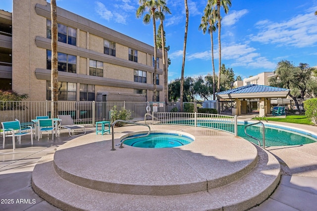 view of pool with fence, a community hot tub, and a patio area
