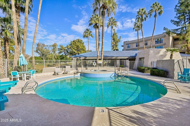 community pool with a patio area and fence