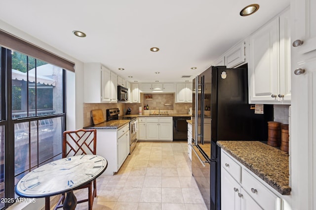 kitchen with decorative backsplash, white cabinetry, a sink, dark stone countertops, and black appliances