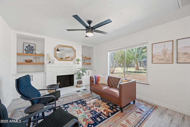 living room with built in shelves, a fireplace, wood finished floors, visible vents, and baseboards