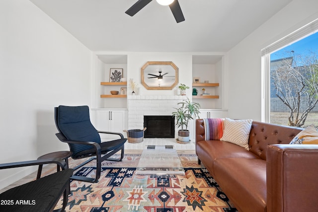 living room with ceiling fan, a healthy amount of sunlight, a brick fireplace, and built in features