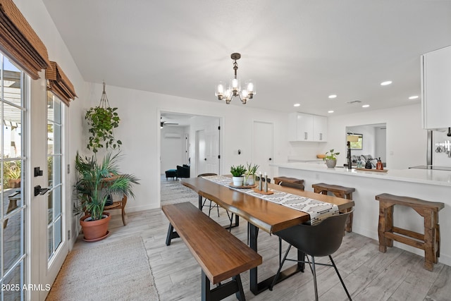 dining space with light wood finished floors, baseboards, a chandelier, and recessed lighting