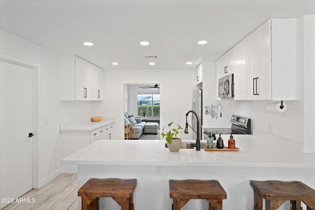 kitchen featuring a peninsula, visible vents, stainless steel appliances, and a breakfast bar area