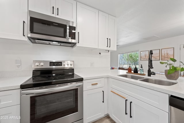 kitchen with appliances with stainless steel finishes, a sink, and white cabinetry