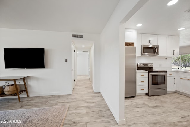 kitchen featuring stainless steel appliances, light wood finished floors, visible vents, and white cabinetry