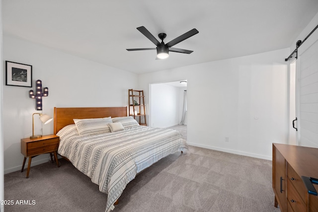 bedroom with a barn door, baseboards, ceiling fan, and carpet flooring