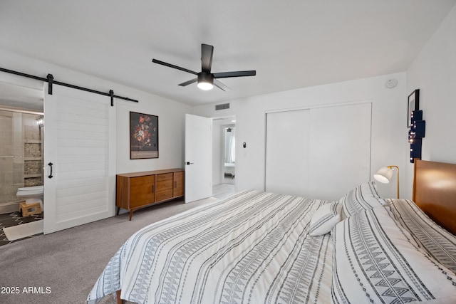 bedroom with ensuite bathroom, a barn door, carpet flooring, visible vents, and a closet