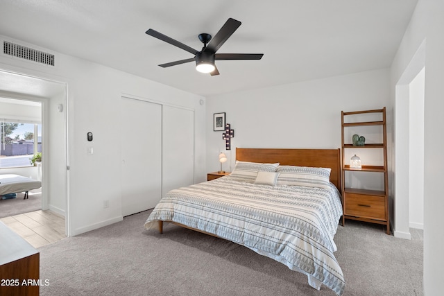 bedroom featuring carpet floors, a closet, visible vents, and ceiling fan