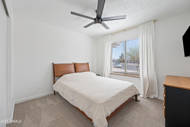 bedroom with baseboards, a ceiling fan, a textured ceiling, and light colored carpet