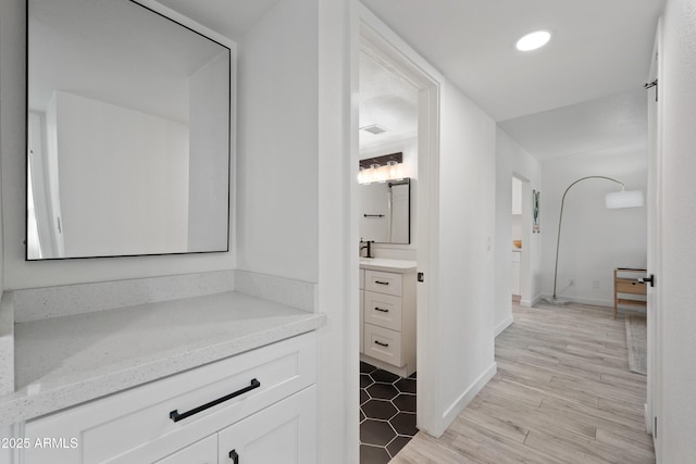 hallway with light wood-type flooring, visible vents, baseboards, and recessed lighting