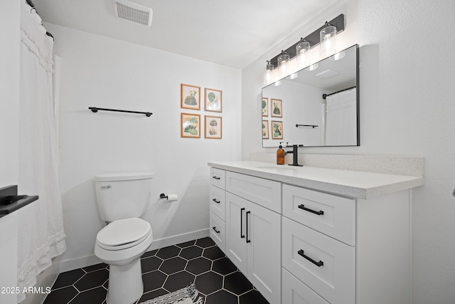 bathroom featuring visible vents, toilet, vanity, baseboards, and tile patterned floors