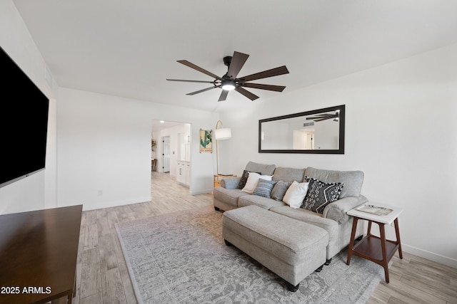 living area featuring a ceiling fan, baseboards, and wood finished floors