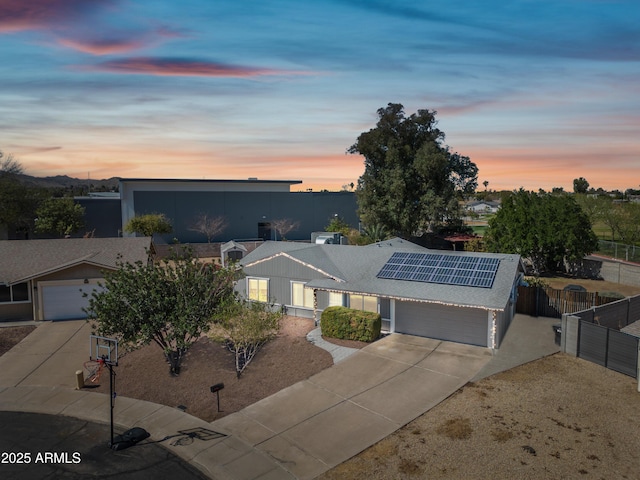 ranch-style house with a garage, solar panels, fence, and concrete driveway