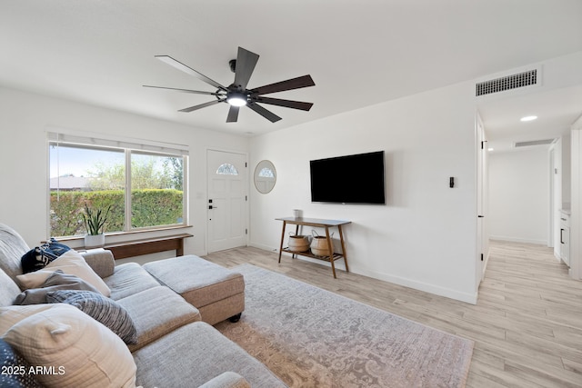 living room featuring light wood-type flooring, baseboards, visible vents, and a ceiling fan