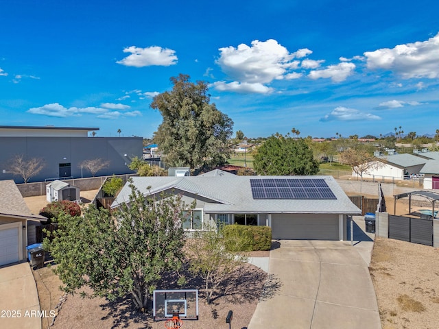 view of front of house featuring a garage, solar panels, fence, driveway, and a residential view