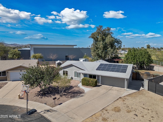 single story home with solar panels, a shingled roof, fence, and concrete driveway