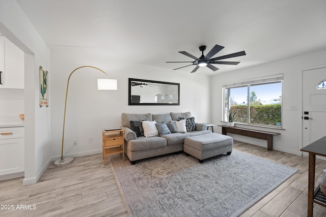 living room featuring light wood-type flooring, ceiling fan, and baseboards