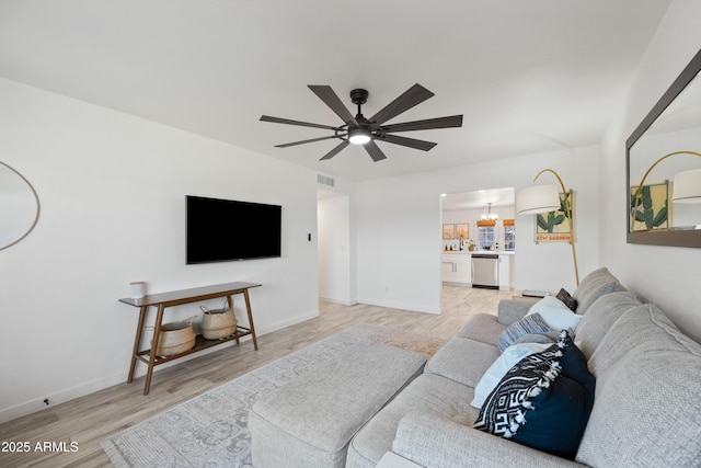 living room with light wood-style floors, visible vents, baseboards, and ceiling fan with notable chandelier