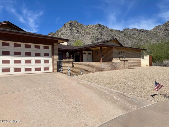 view of front facade featuring a mountain view, brick siding, an attached garage, and driveway