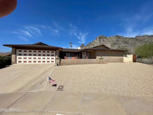 view of front of property featuring concrete driveway, an attached garage, fence, and brick siding