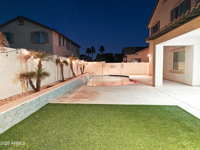 yard at night with a fenced in pool and a patio