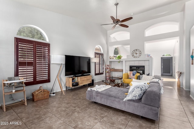 living room with ceiling fan, a fireplace, and high vaulted ceiling