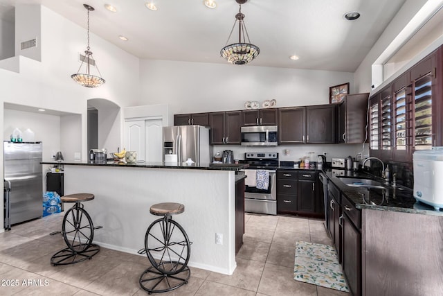 kitchen with hanging light fixtures, appliances with stainless steel finishes, a center island, and a kitchen bar