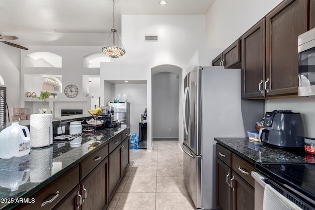 kitchen featuring pendant lighting, dark brown cabinets, dark stone counters, and light tile patterned flooring