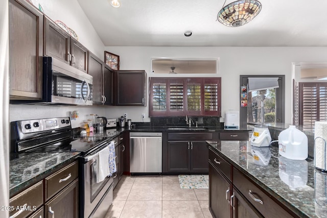 kitchen featuring dark brown cabinetry, appliances with stainless steel finishes, sink, and dark stone counters