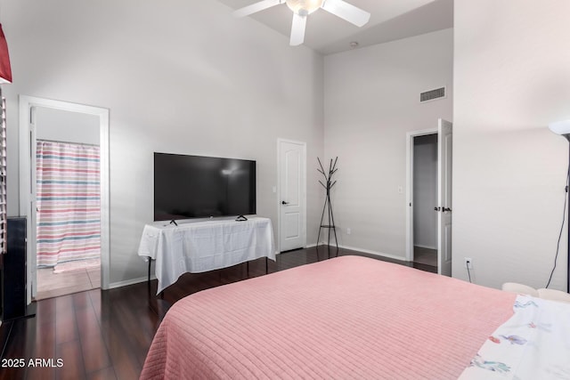 bedroom with ceiling fan, dark hardwood / wood-style flooring, and a towering ceiling