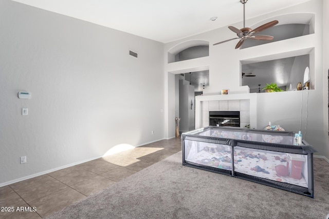 living room featuring ceiling fan, a fireplace, and tile patterned flooring