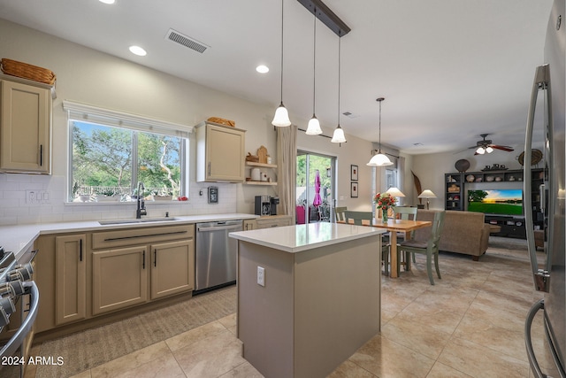 kitchen with sink, a kitchen island, appliances with stainless steel finishes, decorative light fixtures, and ceiling fan