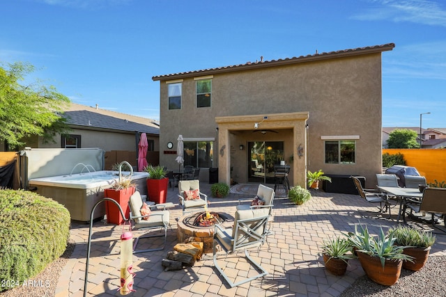 rear view of property featuring a fire pit, a jacuzzi, a patio, and pool water feature